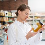 Junge Frau sieht sich den Aufdruck einer Etikett im Supermarkt genau an